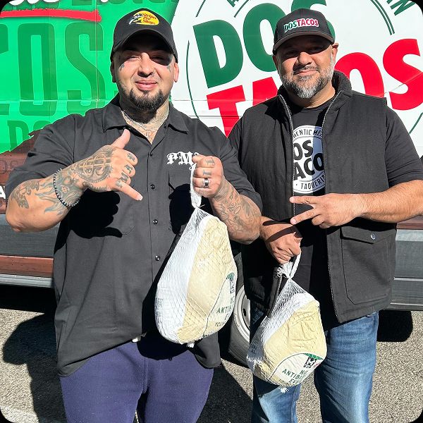 Jamal Abed, founder of Dos Tacos Taqueria and Rrick Pmaf Robles standing in front of the catering van, holding packaged turkeys for thanksgiving donations.